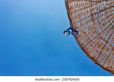 Swim Goggles Hanging On A Parasol Umbrella. View From Directly Below With Copy Space. Clear, Sunny, Open Sky.