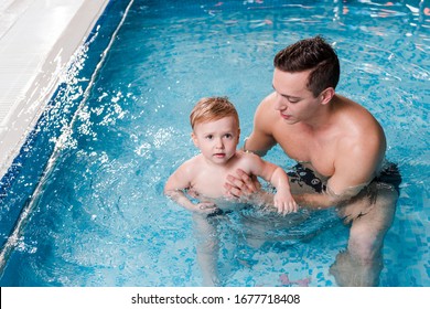 Swim Instructor Teaching Cute Toddler Boy In Swimming Pool