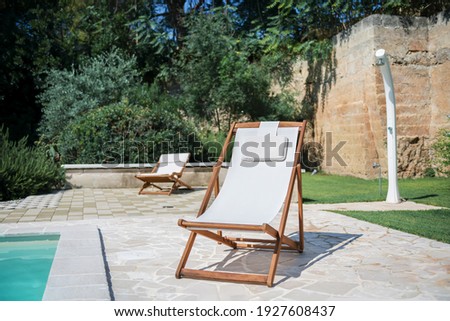 Swim pool with clear blue water and two sun bed on sunny day in a yard, beautiful vacation for relaxation and leisure, concept of mindfulness well being, happiness and slow life