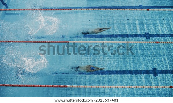 Swim Race: Two Professional\
Swimmers Dive in Swimming Pool, Swimming Underwater. Athletes\
Compete the Best Wins Championship, World Record. Aerial Top View\
Shot