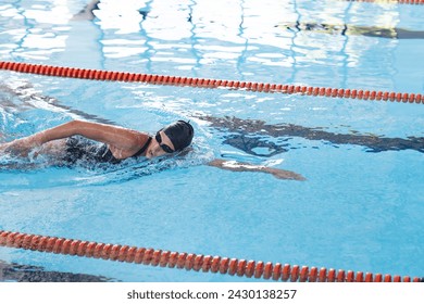 Swimmer in action at an indoor pool. The athlete demonstrates competitive swimming technique in a sports facility. - Powered by Shutterstock