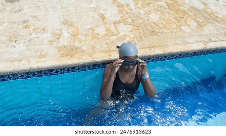 Swimmer adjusting goggles while standing in the pool, wearing swim cap and goggles. - Powered by Shutterstock