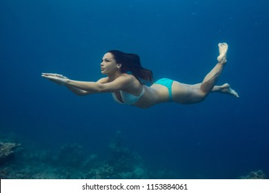 Swimmer Brunette Diving Deep In Ocean On Blue Underwater Background