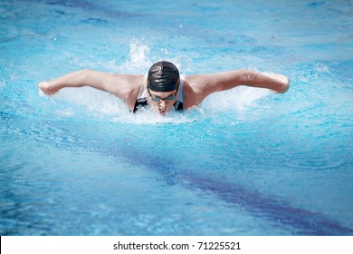 Swimmer in cap breathing performing the butterfly stroke
