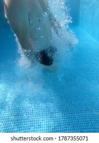 Swimmer Coming Out Of The Blue Pool Surrounded By Bubbles In The Water. Vertical Photo With Negative Space.