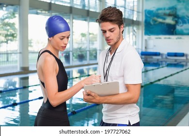 Swimmer discussing times with her coach by the pool at the leisure center - Powered by Shutterstock