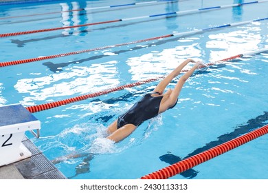 Swimmer dives into a pool at a competitive event, with copy space. Captured at the moment of entry, the athlete's form is crucial for a good start. - Powered by Shutterstock