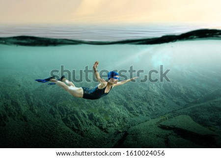 From below full body of unrecognizable active teen boy wearing yellow flippers snorkeling by coral reef in deep ocean with crystal clear waters at Menorca