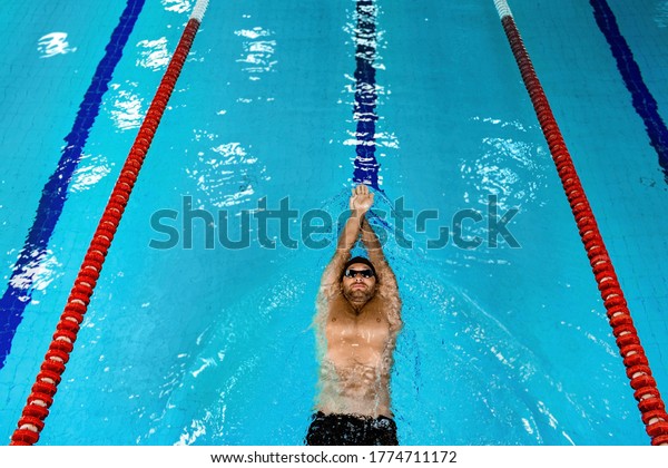 Swimmer floating in the swimming pool, top view. Man\
swimming on back