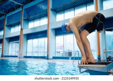 Swimmer with a leg disability on starting block preparing to jump into the pool. Copy space. - Powered by Shutterstock