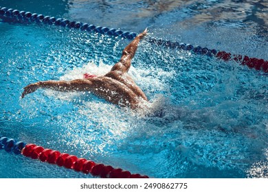 swimmer, sportsman performs powerful butterfly stroke, his muscular form creating dynamic splash as they glide through clear blue pool. Concept of aquatic sport, preparation to competition, energy. - Powered by Shutterstock