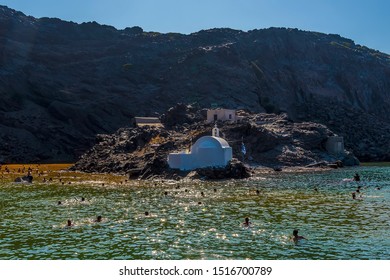 Swimmers head towards the thermal springs on the volcanic island of Palea Kameni, Santorini in summertime