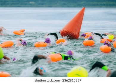 swimmers in open water at the start with a buoy