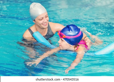 Swimming Class - Little Girl Learning To Swim With Swimming Instructor