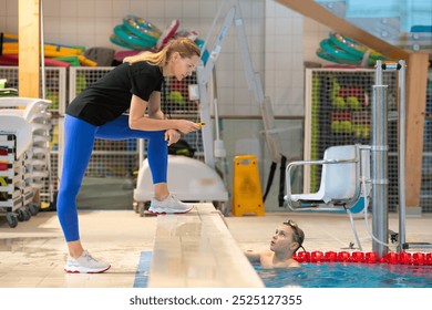 Swimming coach gives instructions to an athlete during training. - Powered by Shutterstock