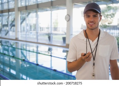 Swimming coach standing by the pool smiling at camera at the leisure center - Powered by Shutterstock