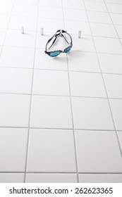 Swimming Goggles Hanging On A Hook On A Tile Wall