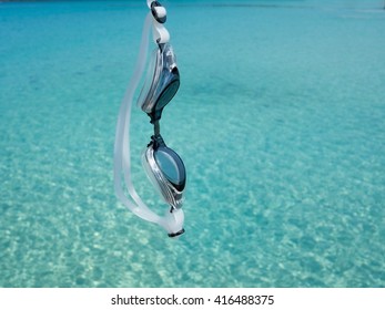 Swimming Goggles Hanging Over Crystal Green Sea.