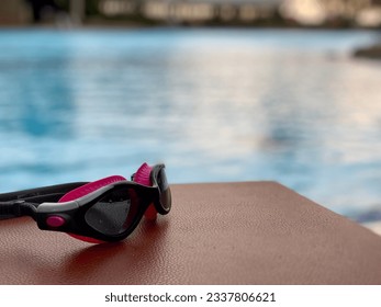 Swimming goggles are placed on a chair by the pool