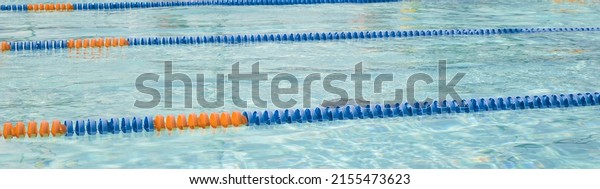 A swimming lap pool with blue and orange\
lane ropesdividers