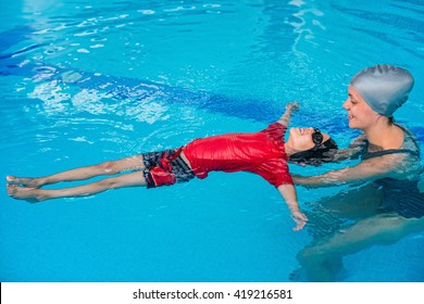 Swimming Lessons For Children - Swimming Instructor Helping Little Boy To Relax In Water