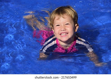 Swimming Lessons: Cute Baby Girl Is Learning How To Swim In The Pool