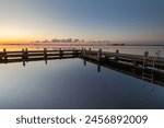 Swimming pontoon on the Alkmaardermeer during a calm sunrise at the recreational area De Hoorne. A calm sunrise  creates a pleasant reflection of the swimming pontoon. 