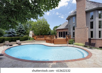 Swimming pool in back of luxury home with wood deck.