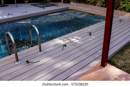 Swimming pool with blue dirty water inside and wooden floors in construction progress