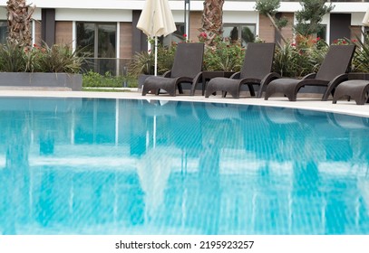 Swimming Pool With Blue Turquoise Water, No People. Beautiful Luxury Resort, Chaise Longues In Hotel Outdoors. Relaxation Concept. Copyspace. 