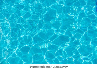 Swimming Pool With Blue Water, Ripples And Highlights. Texture Of Water Surface And Tiled Bottom. Overhead View. Summer Background.