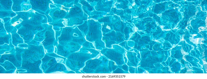 Swimming Pool With Blue Water, Ripples And Highlights. Texture Of Water Surface And Tiled Bottom. Overhead View. Summer Background.