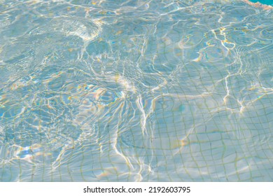 Swimming Pool With Blue Water, Ripples And Highlights. Texture Of Water Surface And Tiled Bottom. Overhead View. Summer Background.