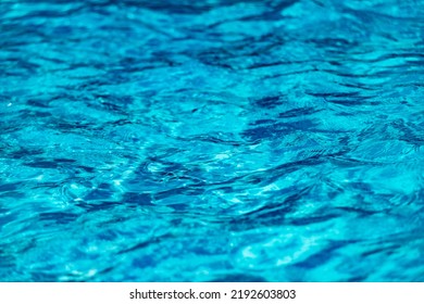 Swimming Pool With Blue Water, Ripples And Highlights. Texture Of Water Surface And Tiled Bottom. Overhead View. Summer Background.