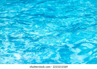 Swimming Pool With Blue Water, Ripples And Highlights. Texture Of Water Surface And Tiled Bottom. Overhead View. Summer Background.