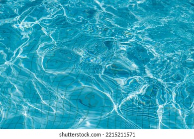 Swimming Pool With Blue Water, Ripples And Highlights. Texture Of Water Surface And Tiled Bottom. Overhead View. Summer Background.