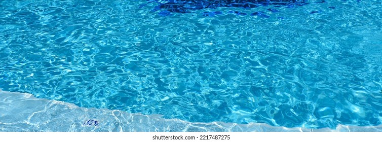 Swimming Pool With Blue Water, Ripples And Highlights. Texture Of Water Surface And Tiled Bottom. Overhead View. Summer Background.