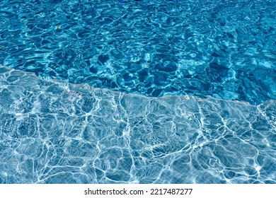 Swimming Pool With Blue Water, Ripples And Highlights. Texture Of Water Surface And Tiled Bottom. Overhead View. Summer Background.