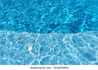 Swimming Pool With Blue Water, Ripples And Highlights. Texture Of Water Surface And Tiled Bottom. Overhead View. Summer Background.