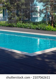 Swimming Pool With Clean Clear Water, Vertical Style, Nobody. Square Shaped Pool With Blue Tiles On The Wood Decks Near The Garden And House, No People. Summer Background.