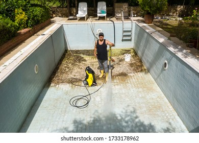 Swimming Pool Cleaning. Dirty pool, A service man is cleaning the pool ground with a pressure pump