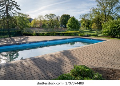 Swimming Pool With Concrete Pavers Just After Opening For The Season With Green Water And Debris