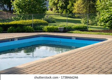 Swimming Pool With Concrete Pavers Just After Opening For The Season With Green Water And Debris