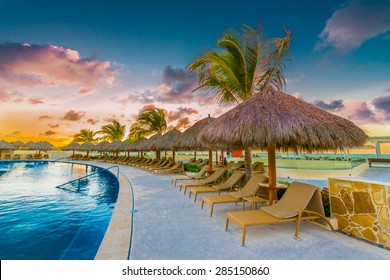 Swimming Pool And A Grass Beach Umbrellas With Lounges At Night, Dawn, Evening Time. Mexico.