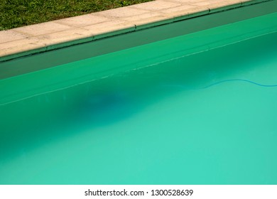 Swimming pool maintenance - An automatic robot pool cleaner can just be seen on the bottom of a cloudy swimming pool removing debris and algae. - Shutterstock ID 1300528639