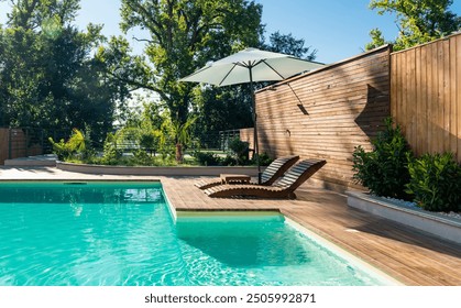 Swimming pool in modern private villa with lounge chairs, palm trees and umbrella - Powered by Shutterstock