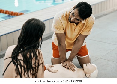 Swimming pool safety, first aid and man teaching life saving process rescue support or helping with danger. Client, emergency CPR and person learning medical service, lifeguard or practice on dummy - Powered by Shutterstock