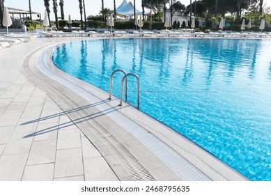 Swimming pool with stair and water. Swimming pool with handrail. Stainless steel ladder in pool. Grab bars ladder in the blue swimming pool - Powered by Shutterstock