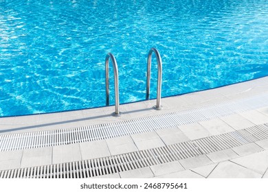 Swimming pool with stair and water. Swimming pool with handrail. Stainless steel ladder in pool. Grab bars ladder in the blue swimming pool