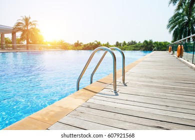 Swimming pool with stair and wooden deck at hotel.